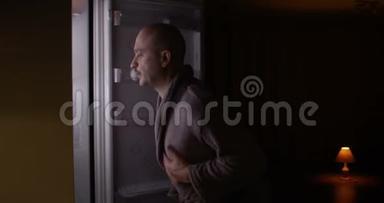 <strong>饥饿</strong>的男人打开空冰箱，在里面寻找食物，失望